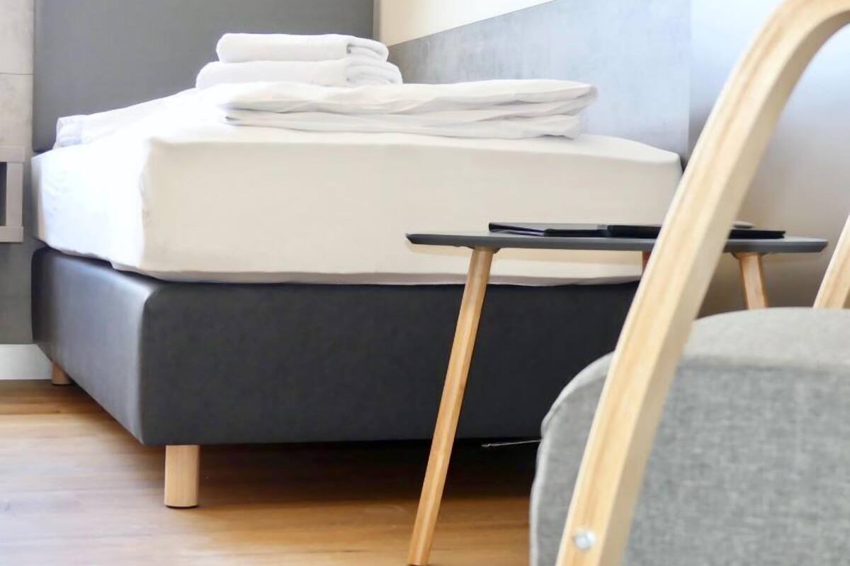 A modern bedroom with a bed, a small bedside table, and a chair.