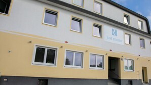 A multi-story building with a sign reading "just rooms" on the facade.