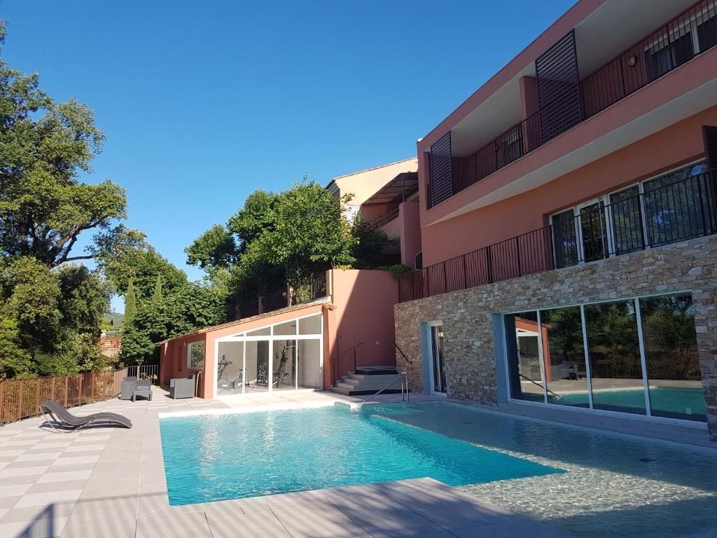 Une maison moderne à deux étages, dotée d’une piscine, de grandes fenêtres et d’un balcon.