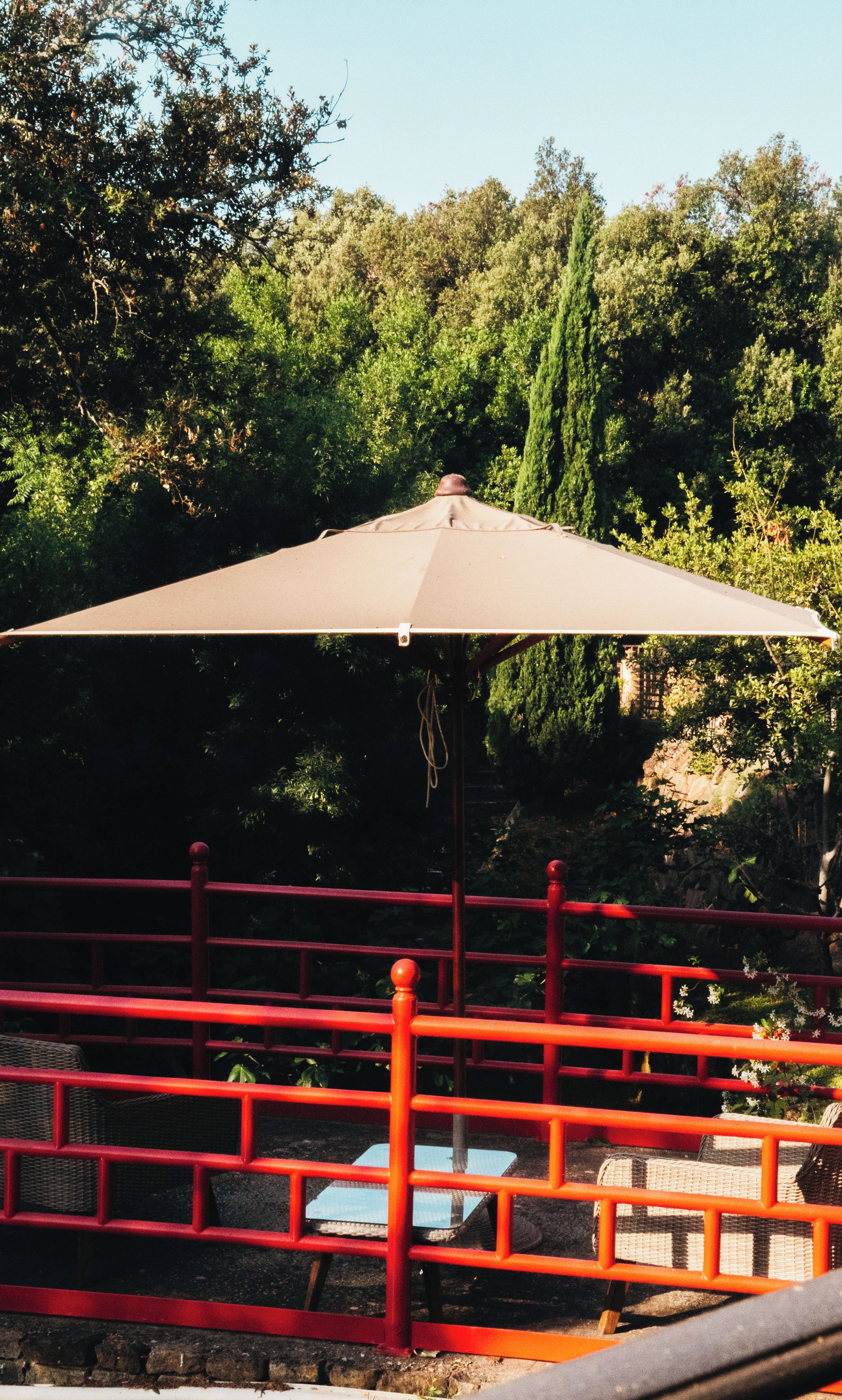 A red metal railing with a bench and a large umbrella structure.