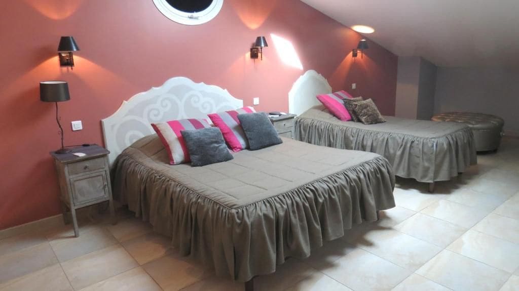 Une chambre à coucher avec deux lits, chacun doté d’une tête de lit et de lampes de chevet.