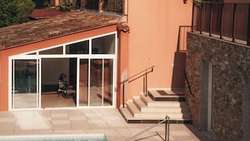 A pool area with a glass-enclosed room, a staircase, and a brick wall.