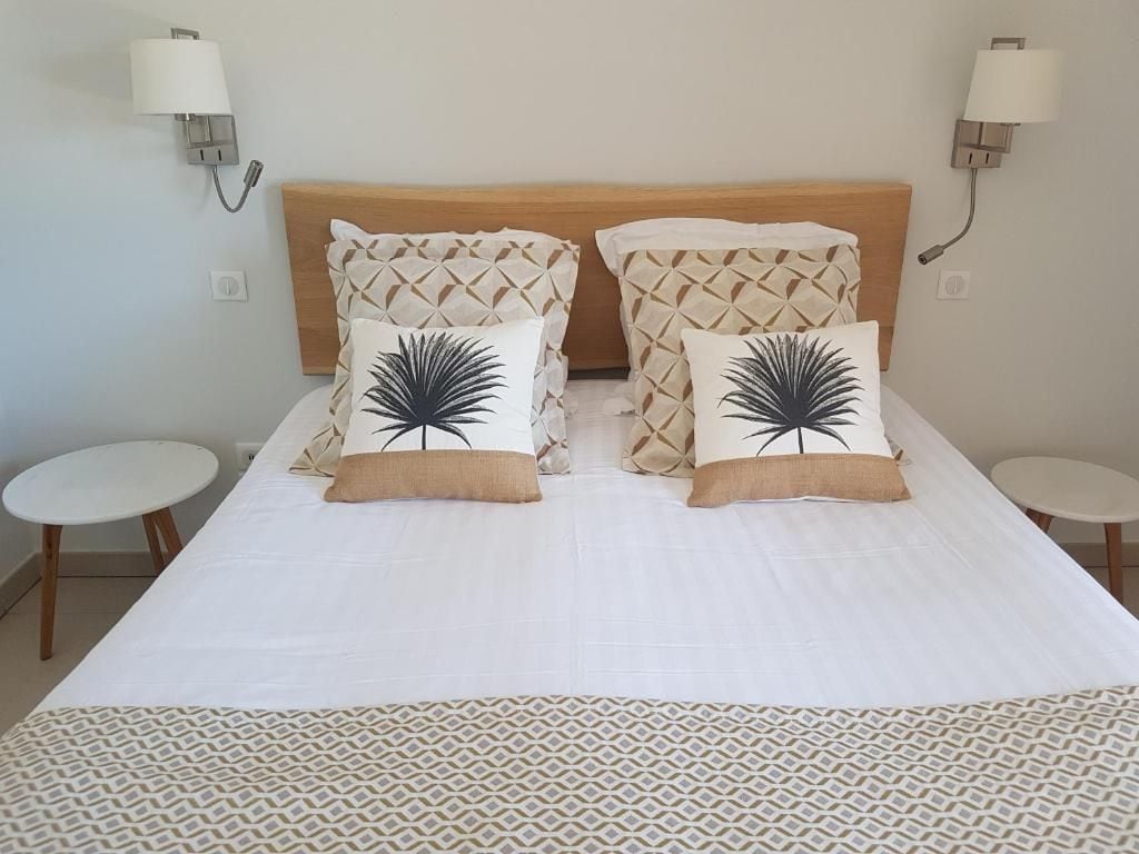 A hotel room with a bed, two bedside tables, and wall-mounted lamps.
