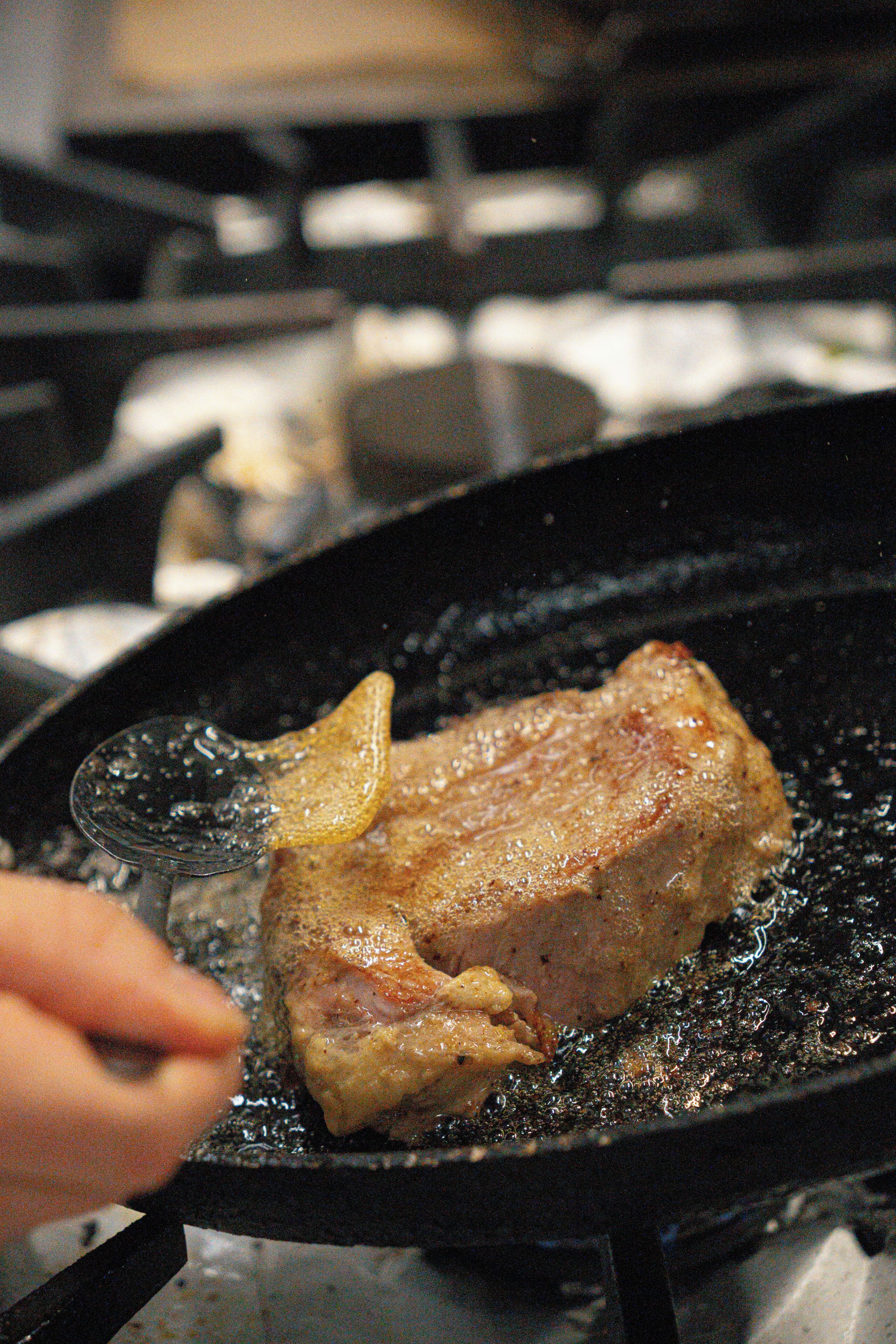 Ein Steak wird in einer Pfanne auf dem Herd gebraten.