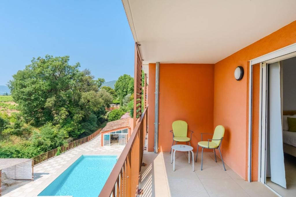 A balcony with a pool, two chairs, and a view of greenery.