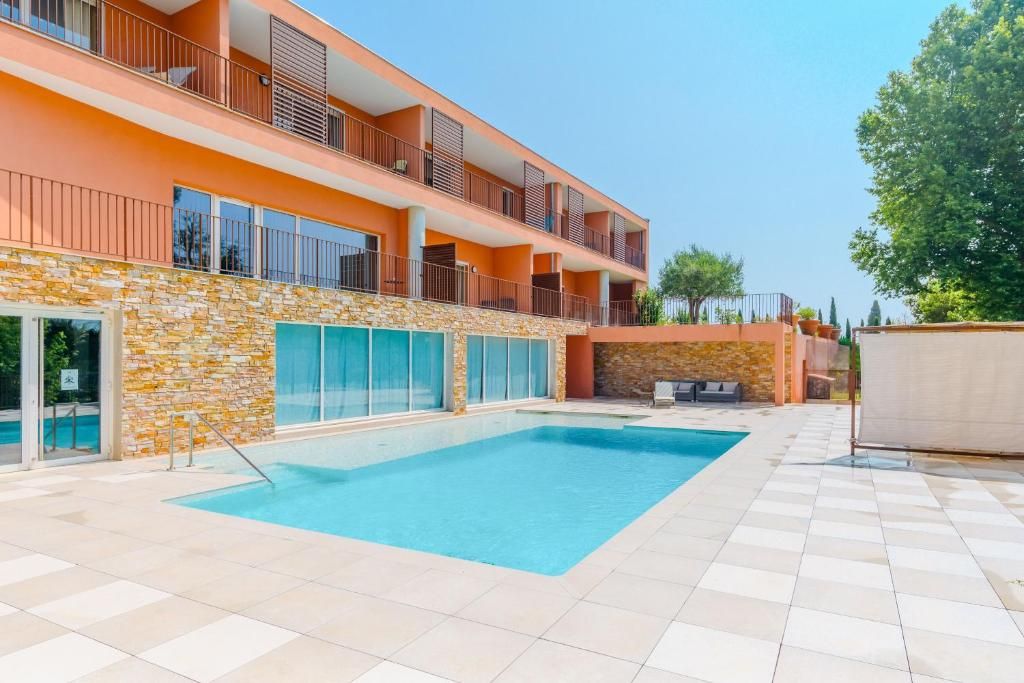 A modern building with a swimming pool, balconies, and a stone facade.