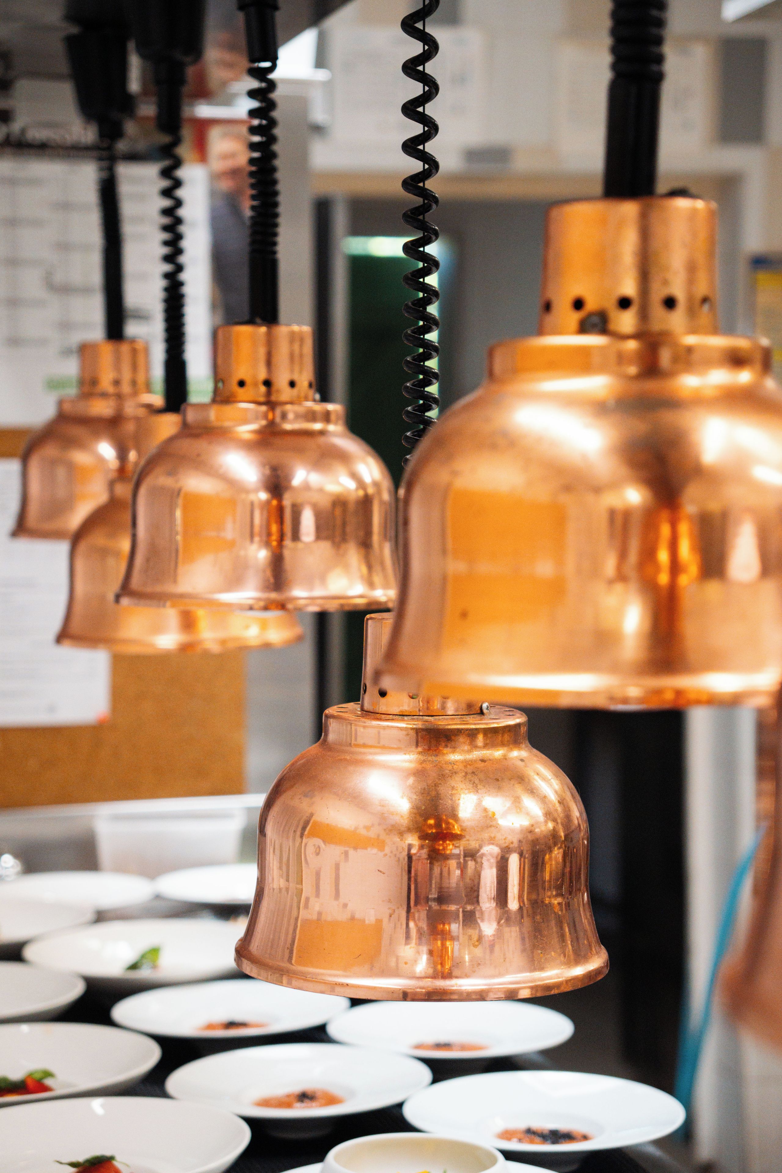 A series of copper-colored pendant lights hanging from a ceiling.