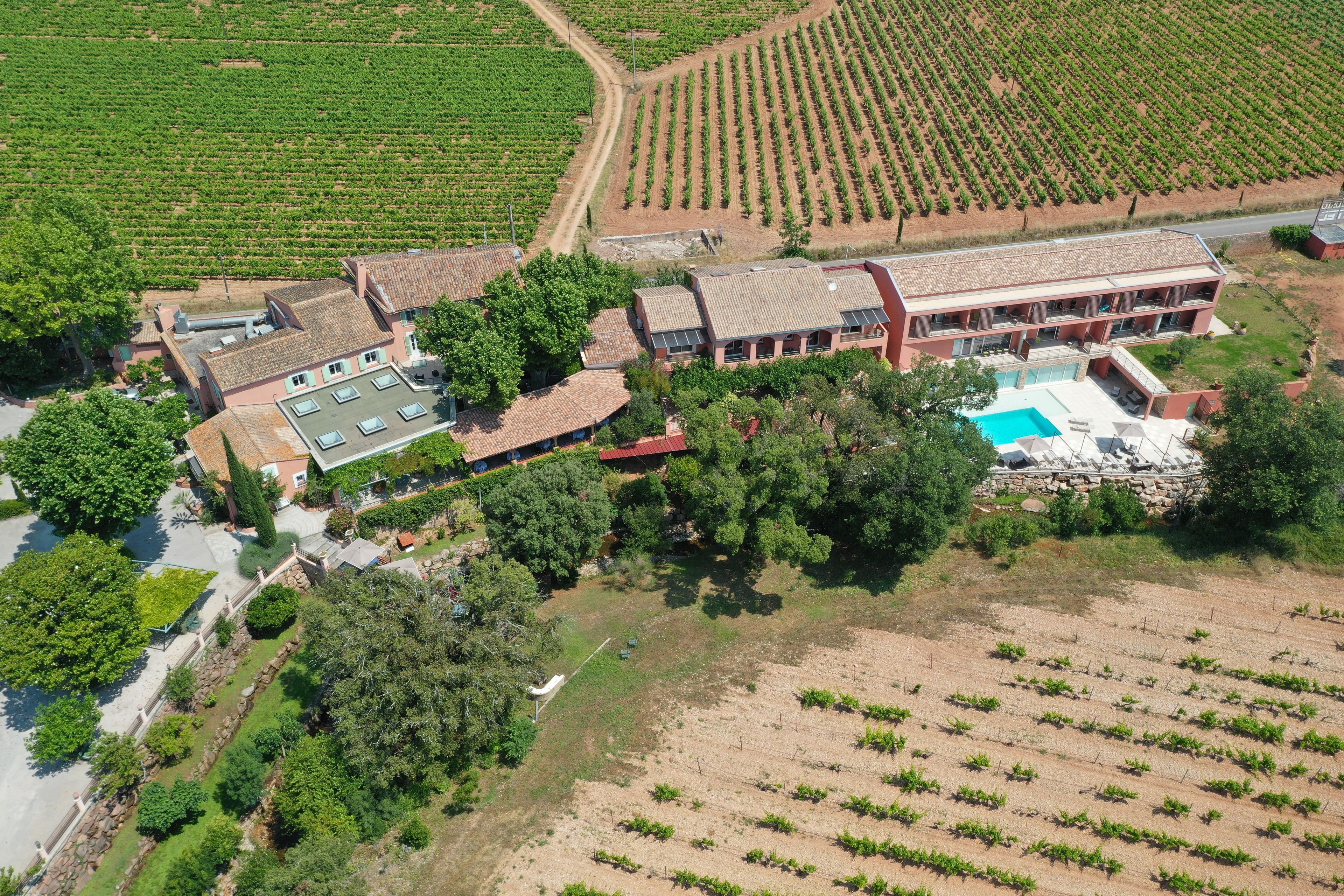 An aerial view of a property with a swimming pool, multiple buildings, and surrounding agricultural fields.