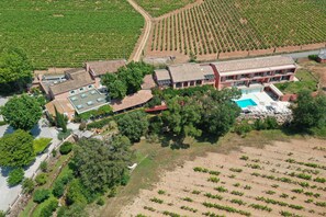 An aerial view of a property with a swimming pool, multiple buildings, and surrounding agricultural fields.