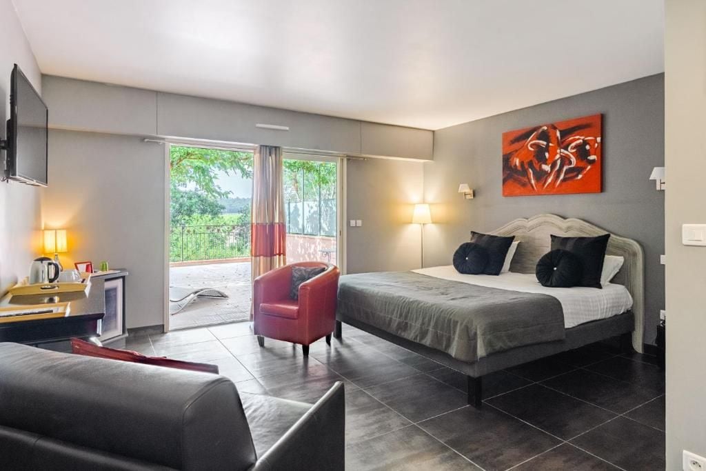 Ein modernes Schlafzimmer mit einem Bett, einem roten Sessel, einem Schreibtisch mit Lampe und einem Fernseher.