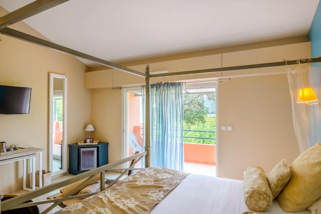 Un dormitorio con cama, televisor, una mesita y una ventana con cortinas.