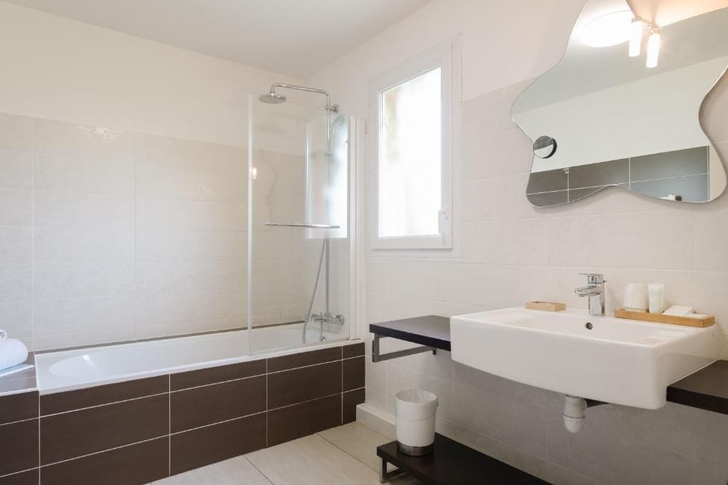 A modern bathroom with a bathtub, shower, and sink.