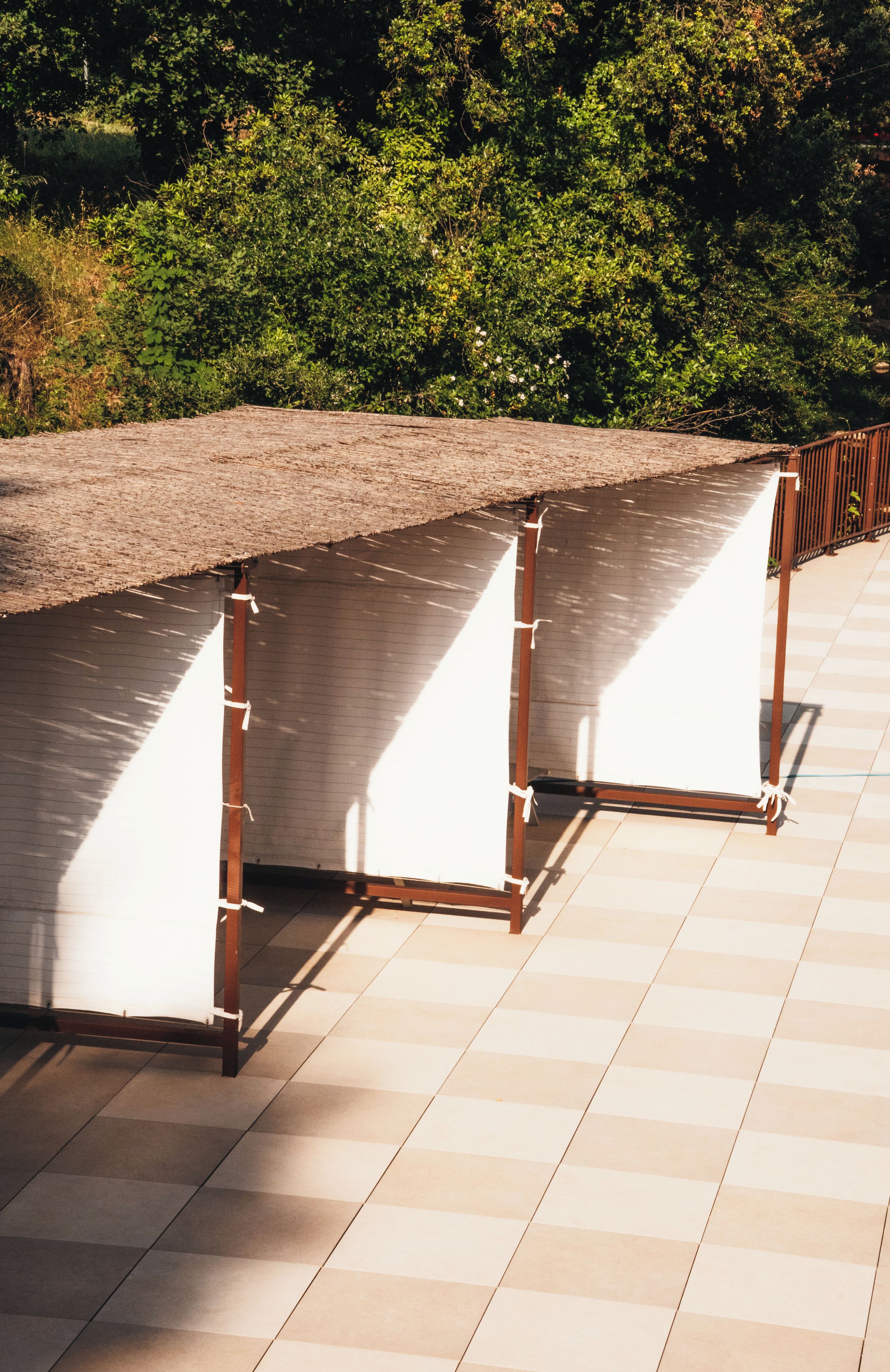 A covered outdoor area with a tiled floor and a metal railing.