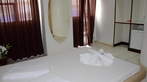 Een hotelkamer met een bed, een tafeltje, een spiegel en een potplant.