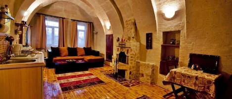 A cozy room with a stone fireplace, wooden flooring, and a sofa.