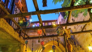 Un patio con faroles decorativos colgantes, paredes de piedra y una escalera de madera.