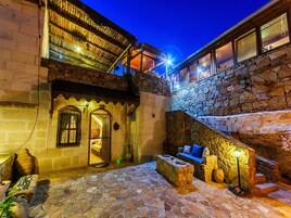 A stone courtyard with a wooden bench, a stone wall, and a staircase.