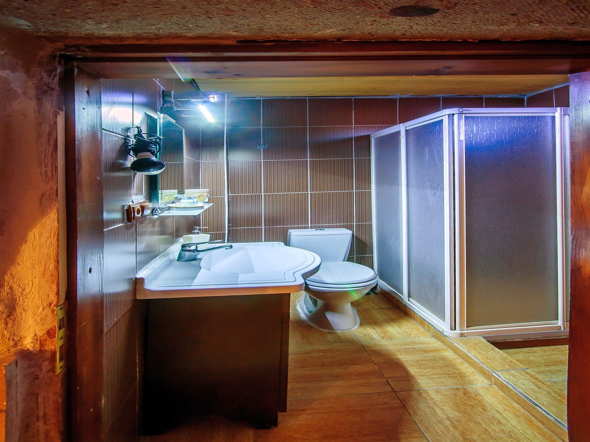 A compact bathroom with a sink, toilet, and shower enclosure.