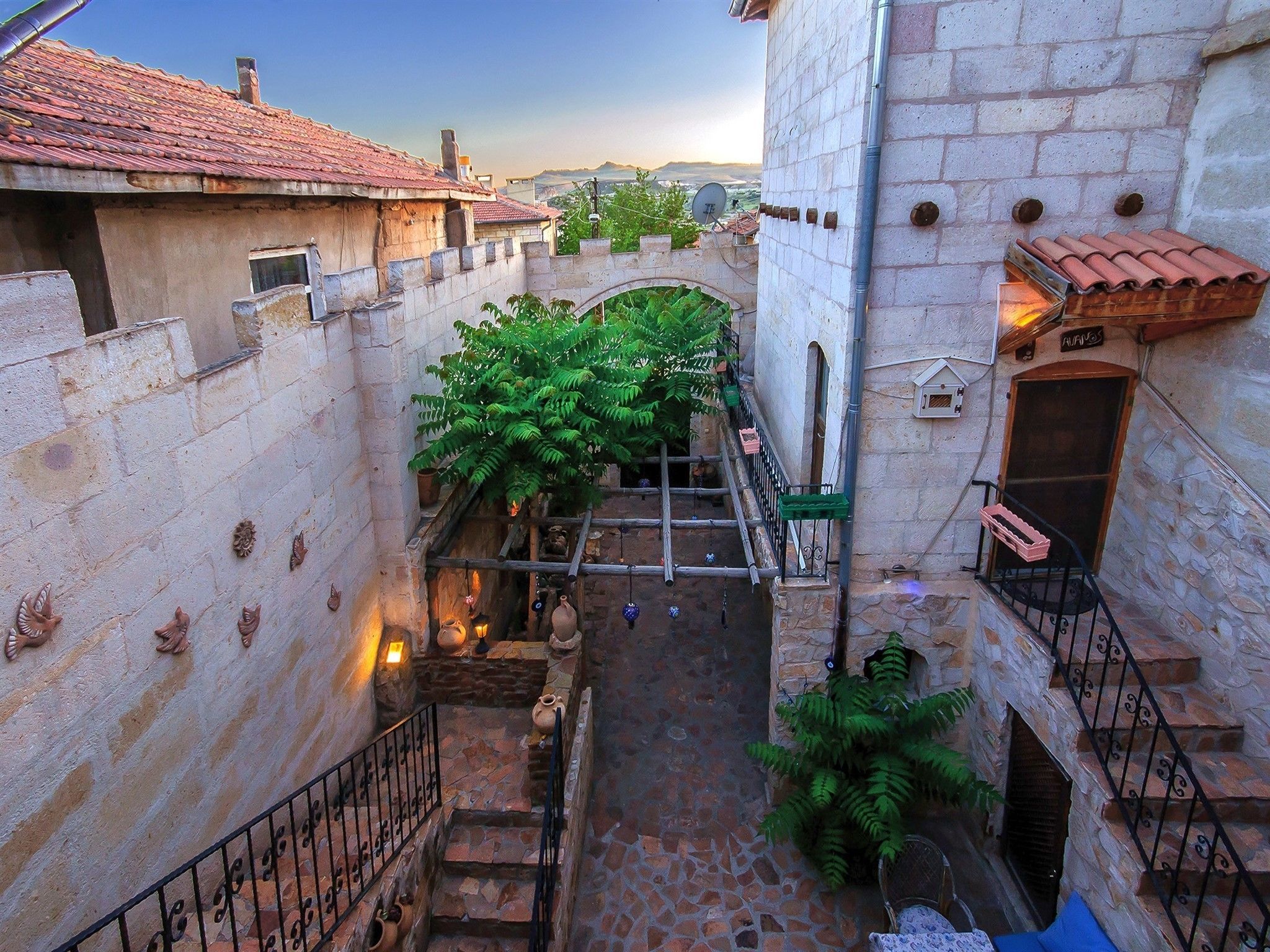 Un estrecho callejón con muros de piedra, tejados de tejas de arcilla y una pequeña escalera que conduce a una puerta de madera.