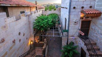 Un estrecho callejón con muros de piedra, tejados de tejas de arcilla y una pequeña escalera que conduce a una puerta de madera.