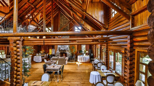 A spacious lodge with a high wooden ceiling, a stone fireplace, and multiple dining areas with tables and chairs. - Tranquilla River Lodge - Adults Only (Sile)