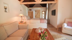 A cozy room with a wooden ceiling, a bed with a pink blanket, a white sofa, and a small table with a vase of flowers. - Tranquilla River Lodge - Adults Only (Sile)