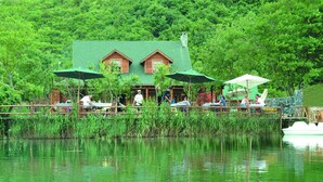 A lakeside lodge with wooden cabins, outdoor dining with umbrellas, and a dock extending into the water. - Tranquilla River Lodge - Adults Only (Sile)