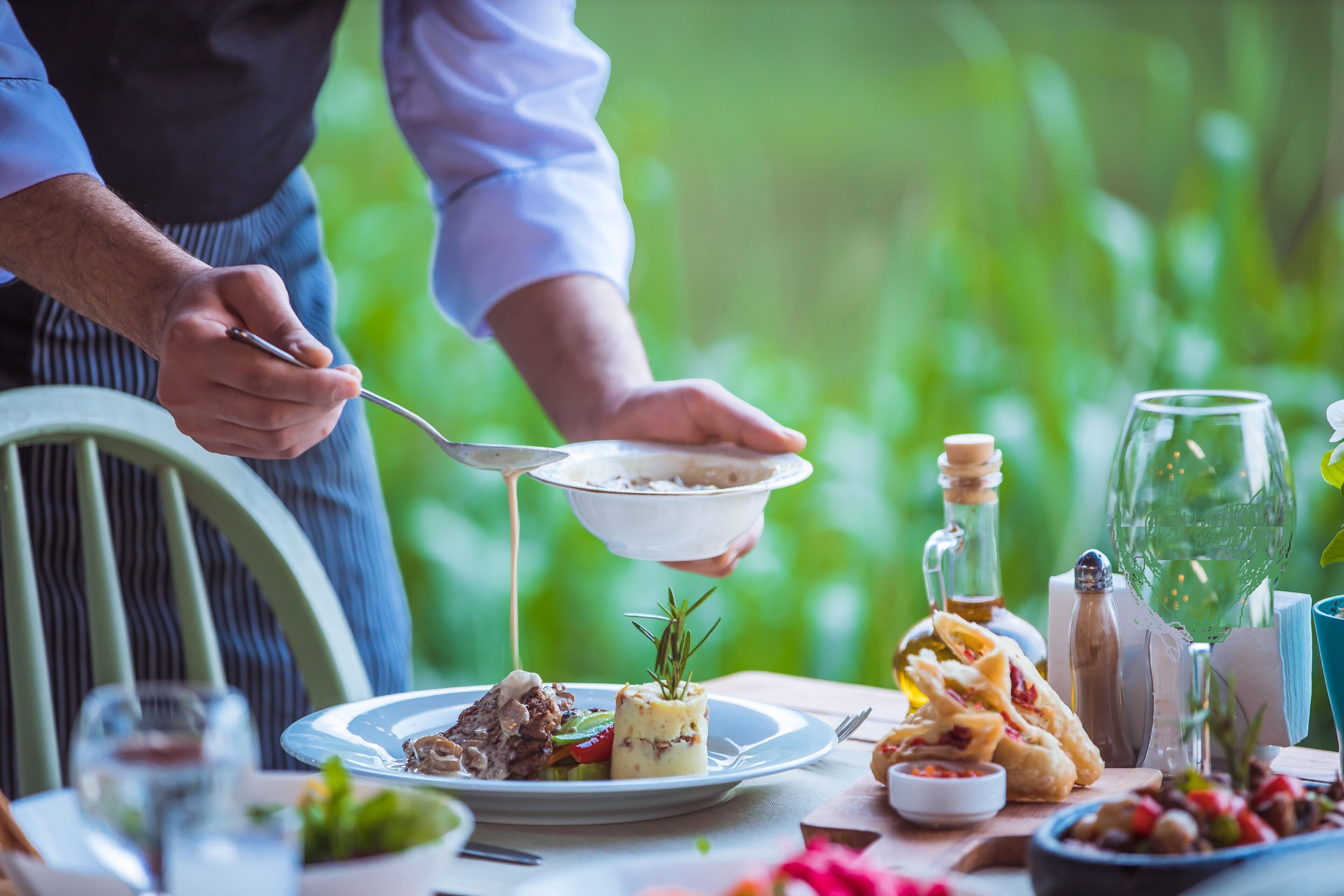A dining table with a variety of dishes, a bottle, and a glass.