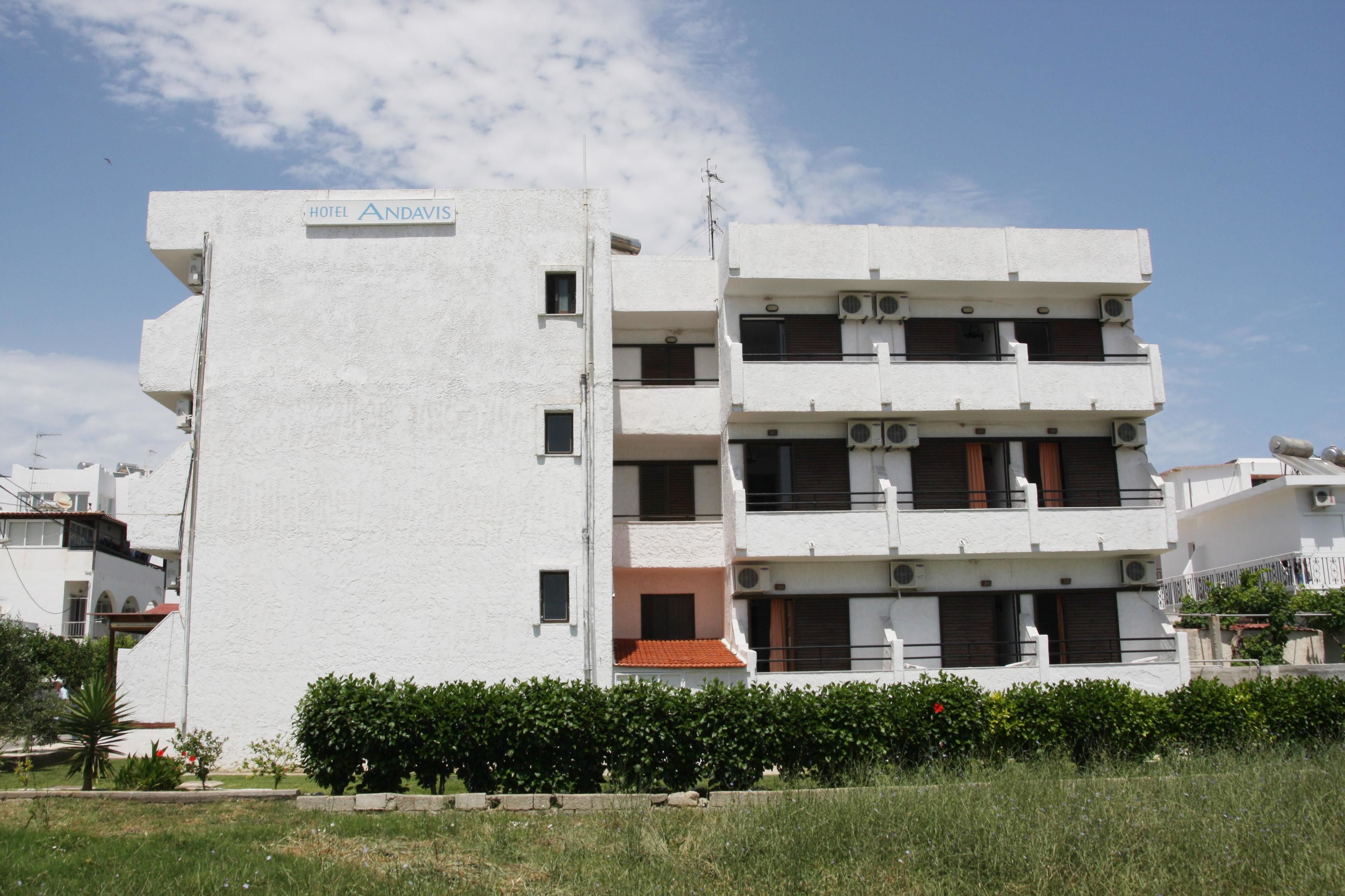 A multi-story hotel with a white facade, balconies, and air conditioning units.