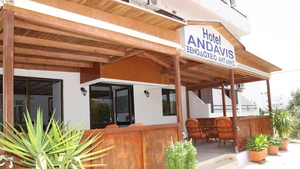 Un hôtel appelé « Hôtel Andavis », doté d’un espace extérieur abrité avec des tables et des chaises, de meubles en bois et de plantes en pot.