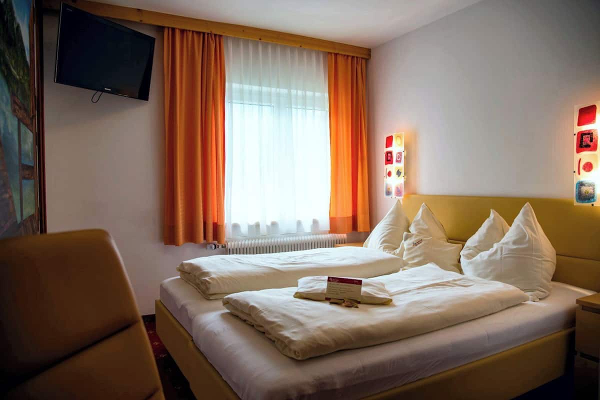 Une chambre d’hôtel avec deux lits, un téléviseur à écran plat, un radiateur et un luminaire fixé au mur.