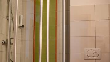 A bathroom with a glass-enclosed shower, a toilet, and a green vertical stripe on the wall.