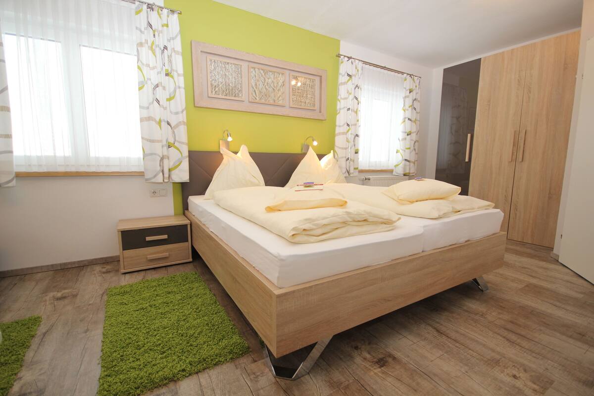 Une chambre à coucher moderne avec un lit en bois, des murs verts et un tapis vert.