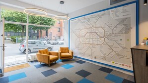A modern lobby with a large map, comfortable seating, and a view of the street outside. - Icke Apartments (Berlin)