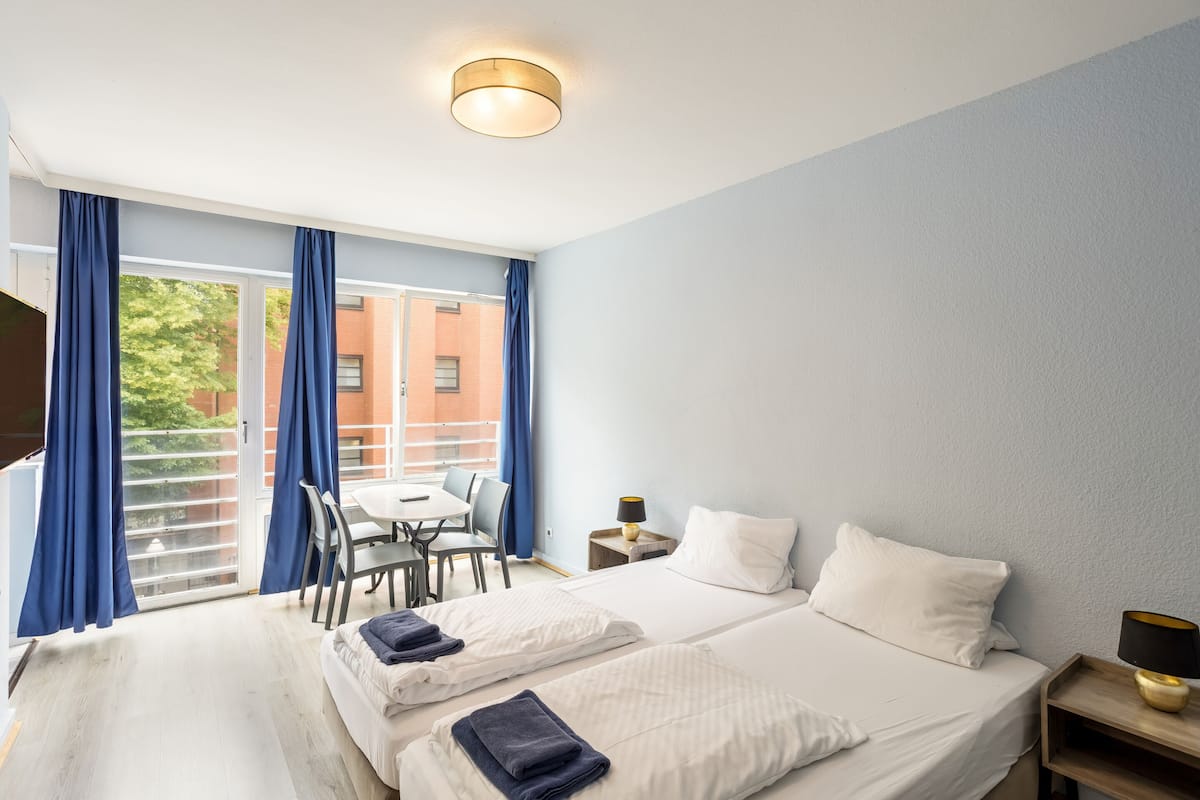 A hotel room with two beds, a desk, and a chair.