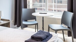 A hotel room with a bed, two chairs, a small table, and a window with curtains. - Icke Apartments (Berlin)