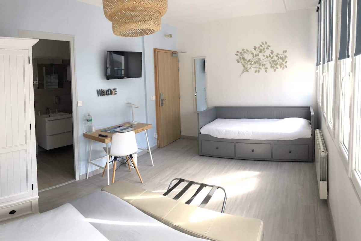 A bedroom with a bed, a desk, a wardrobe, and a TV.