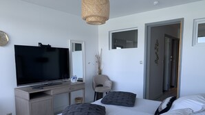 Una habitación de hotel moderna con una cama grande, un televisor de pantalla plana, un escritorio y una silla.