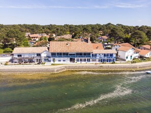 A coastal building with a tiled roof, adjacent to a waterfront. - Le Relais du Lac (Soorts-Hossegor)
