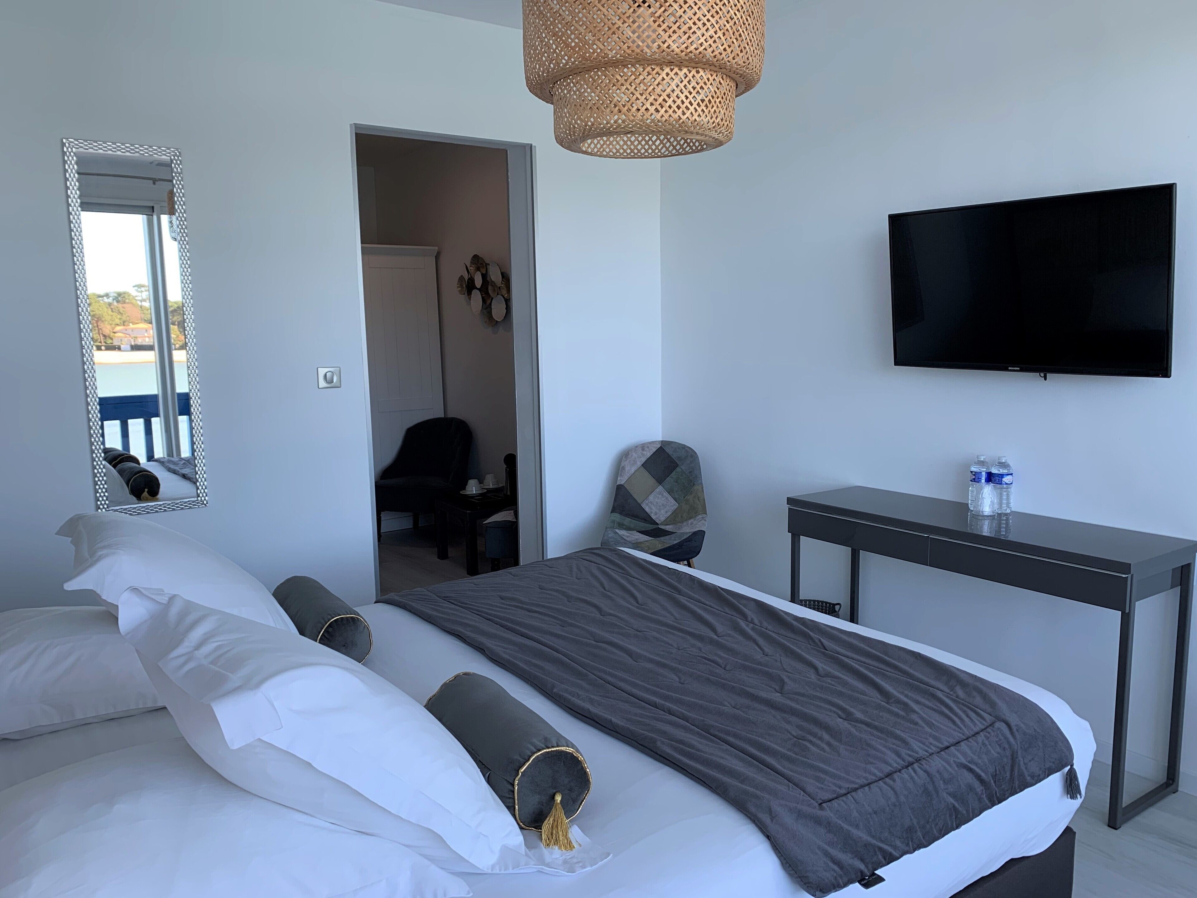 Une chambre d’hôtel avec un lit, un bureau, une télévision et un miroir.