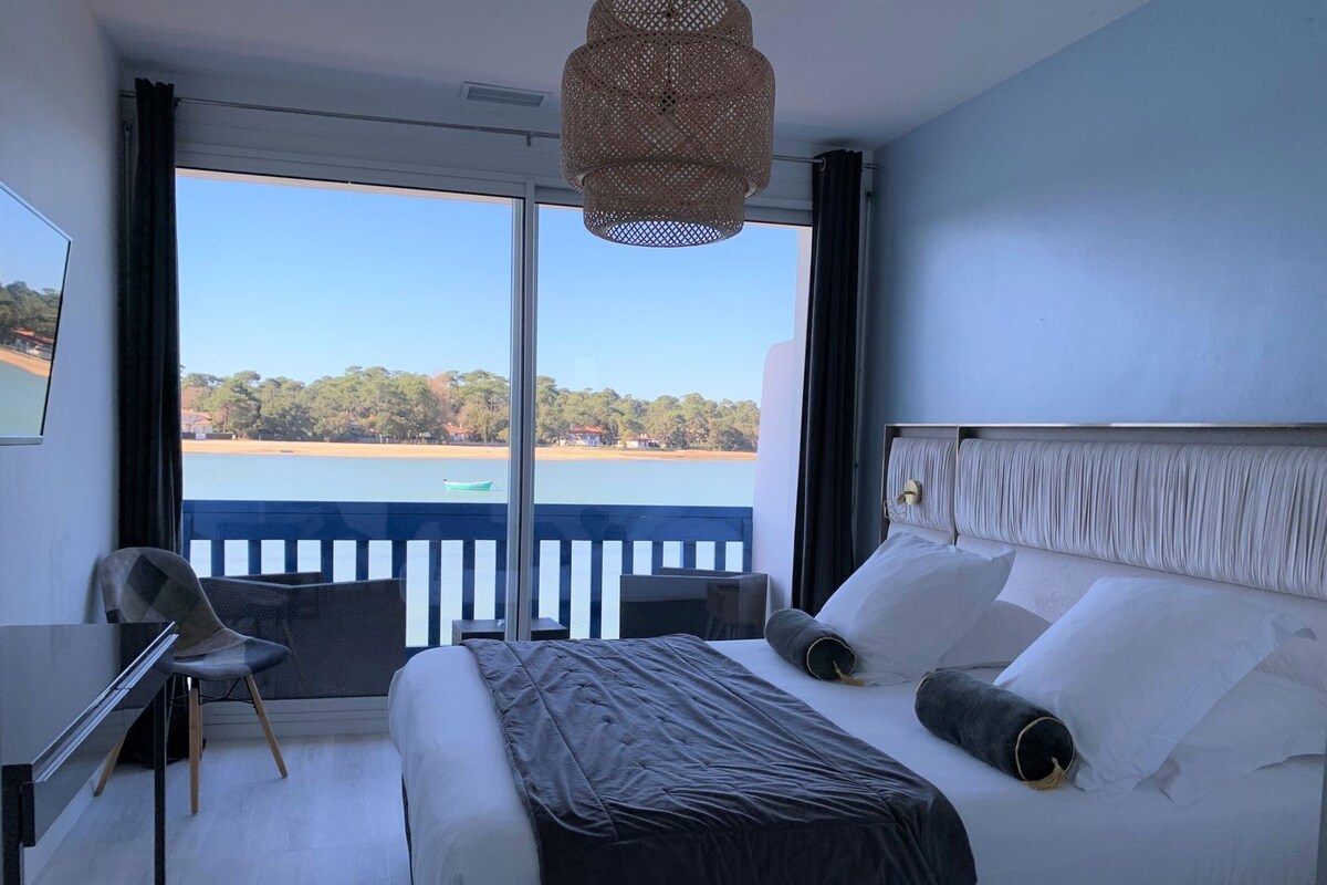 A hotel room with a bed, a desk, and a view of a body of water.