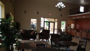 A spacious lobby with leather sofas, a coffee table, and a chandelier. - Montigo Inn (Leesville)