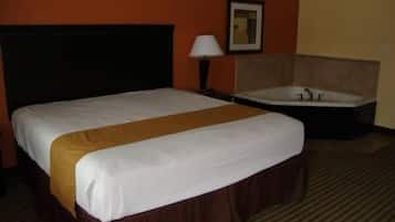 Habitación de hotel con una cama grande, cabecero, lámpara de noche, un cuadro enmarcado en la pared y una bañera.