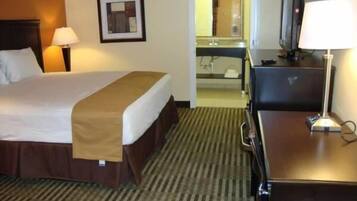 A hotel room with a bed, a desk, a television, and a mirror.