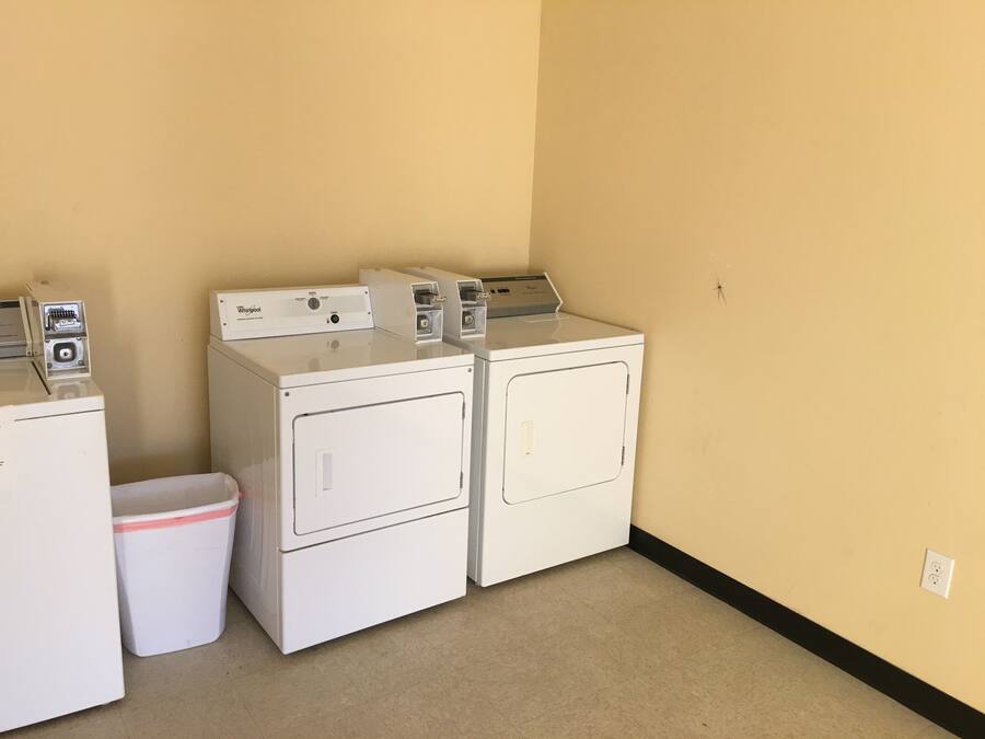A laundry room with two stacked front-loading washers and a single dryer.