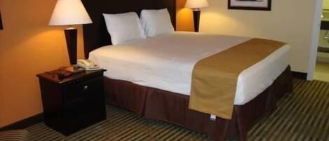 Habitación de hotel con una cama grande, dos mesitas de noche con lámparas, un cuadro enmarcado en la pared y una alfombra a rayas.