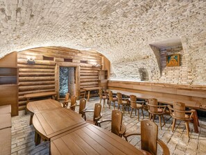 Ein rustikales Blockhaus-Interieur mit Holztischen und -stühlen, einer Steinwand und einem Kamin.