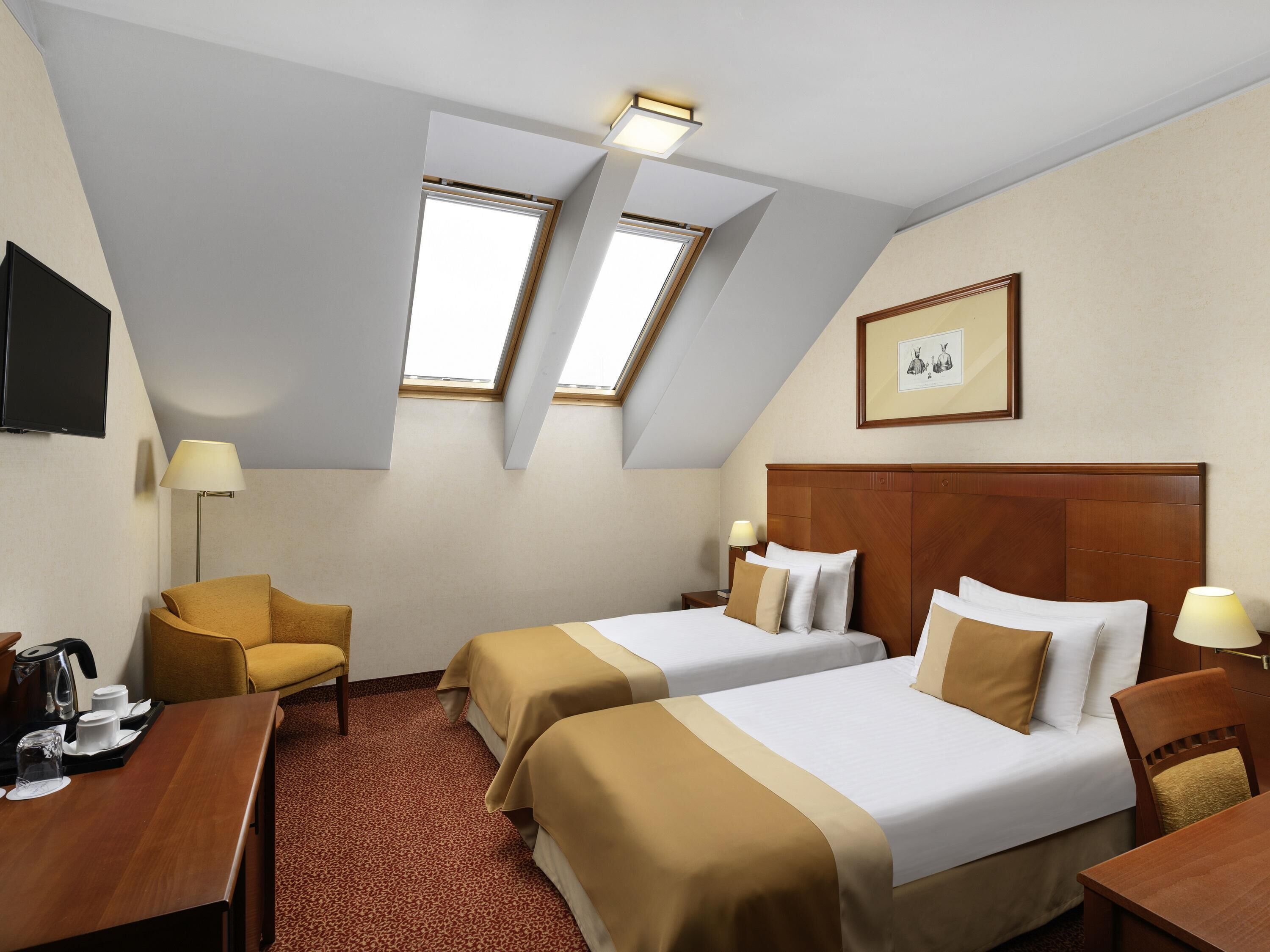 A hotel room with two beds, a desk, a chair, a TV, and a picture on the wall.