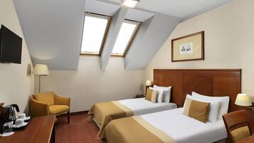 A hotel room with two beds, a desk, a chair, a TV, and a picture on the wall.