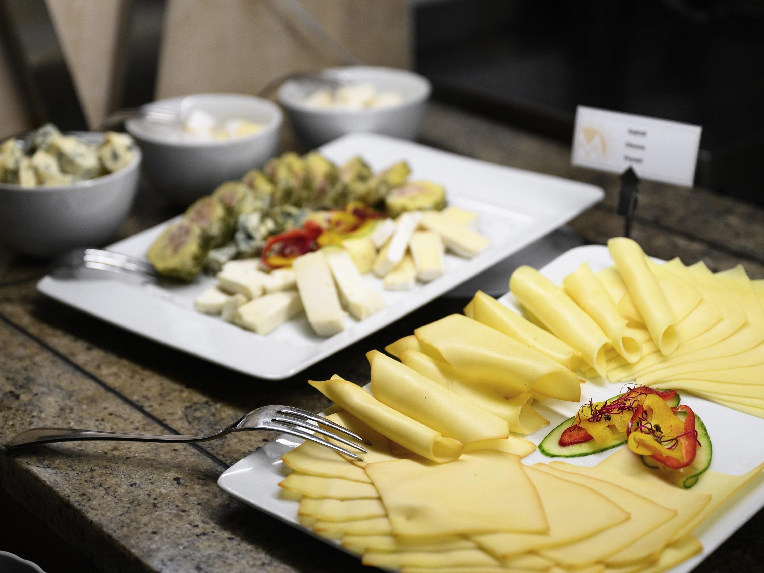 Una mesa de buffet con diversos platos, incluyendo pasta, queso y una ensalada.